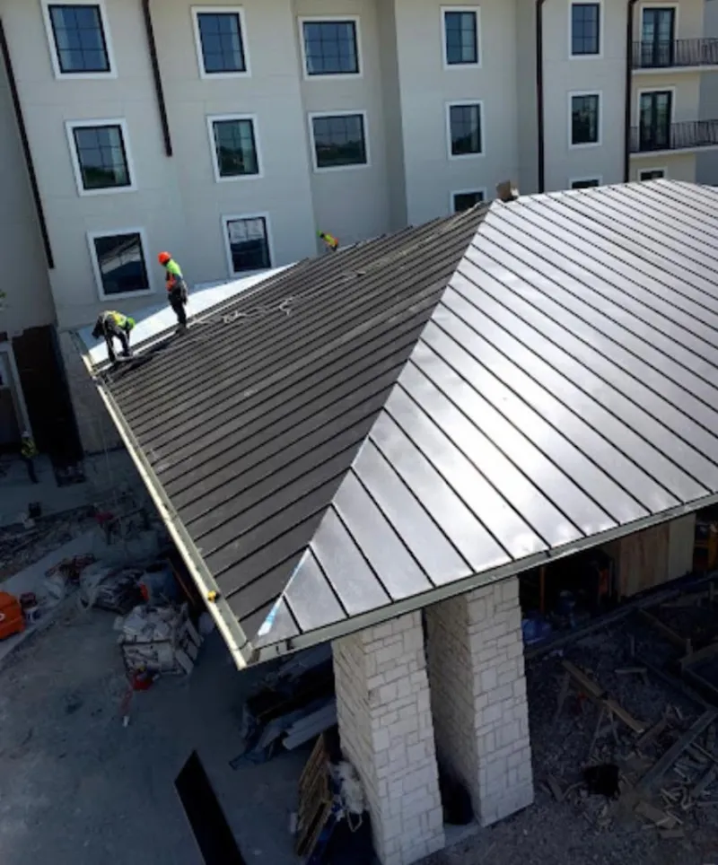 Crew installing standing seam metal roof panels on a commercial project in Tallmadge